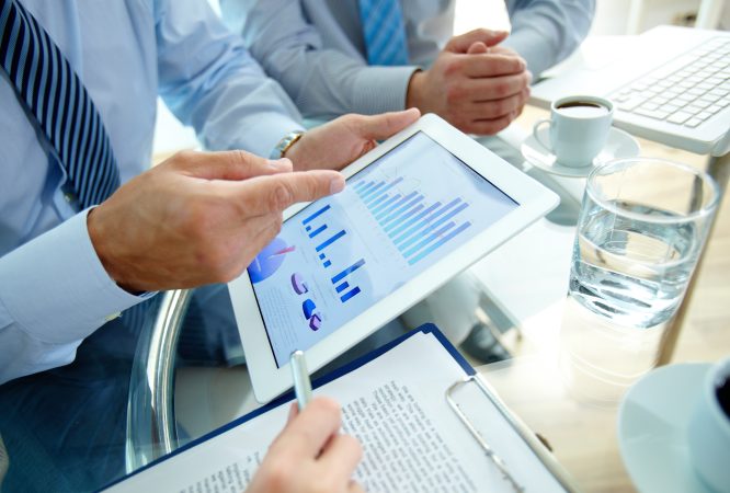 Modern people doing business, graphs and charts being demonstrated on the screen of a touchpad